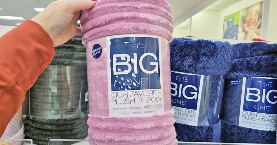 hand holding up purple ribbed throw blanket in store