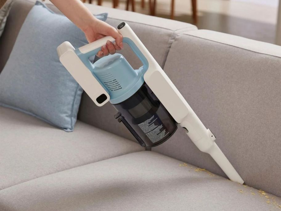 hand using the handheld portion of a Tineco Go 205 vacuum to clean a couch crevice