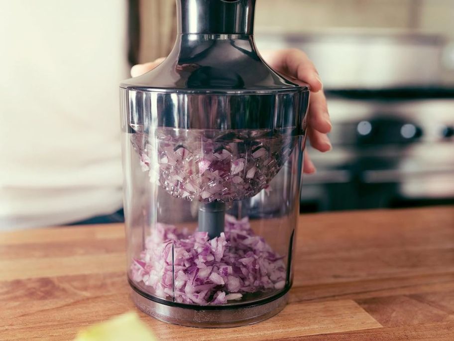 Hand using a Philips hand blender to chop red onions