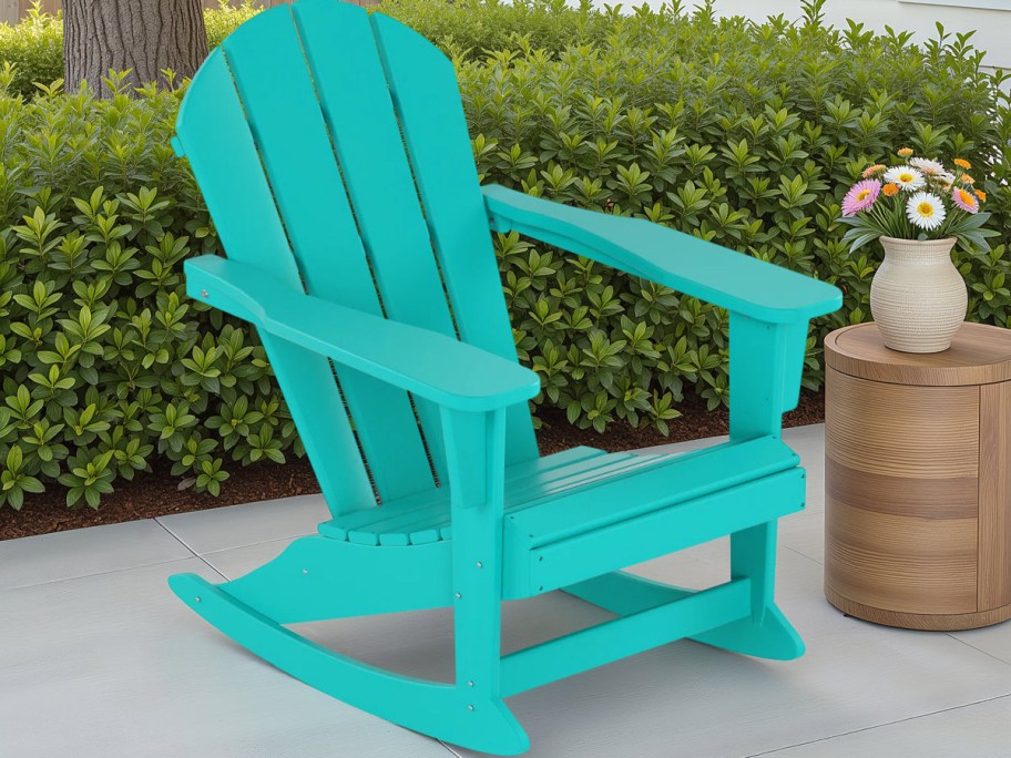 Turquoise Adirondack chair on patio, near a wooden side table with colorful flowers in a vase.
