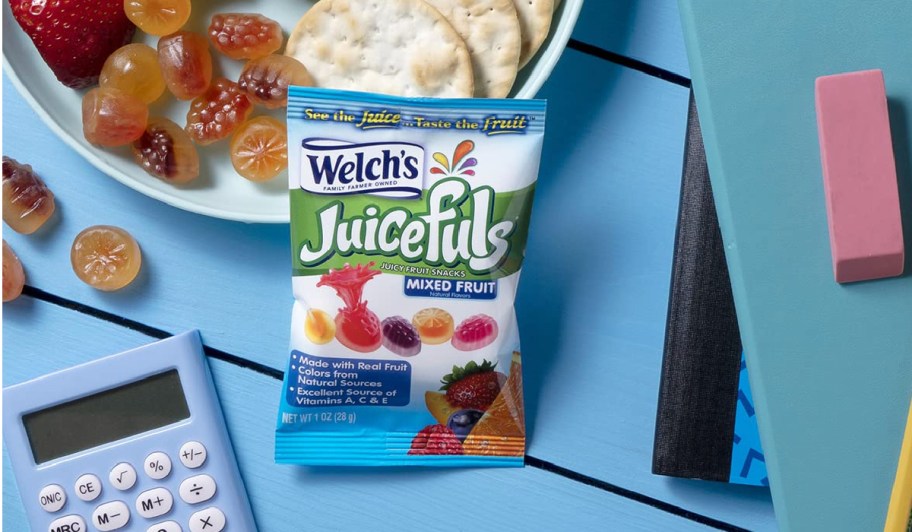 Welchs juicefuls snack bag on blue table top next to school supplies and plate of food