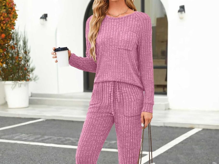 Woman wearing pink lounge set with purse and coffee in hand
