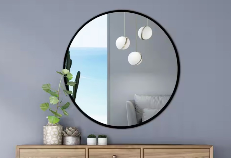 round black framed mirror on a grey wall