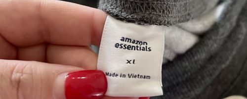 a woman holding an amazon essentials clothing tag