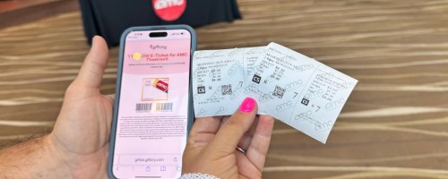 hand holding phone and two movie tickets