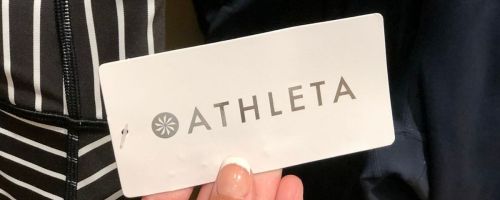 a womans hand holding an athleta clothing tag
