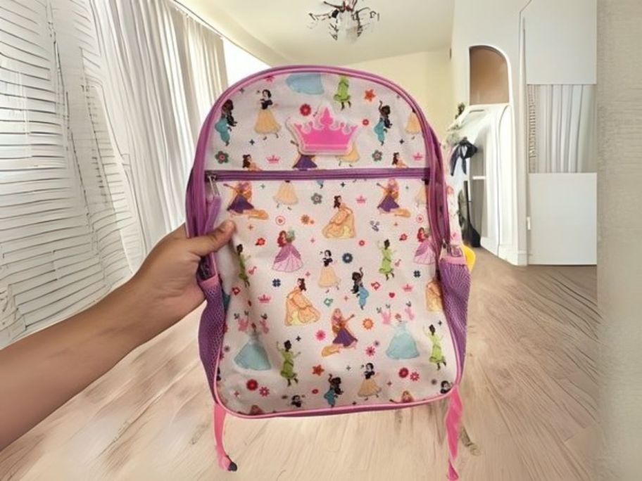 hand holding disney princesses backpack