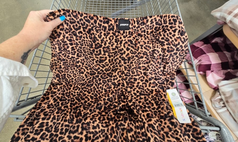 a woman's hand holding the corner of the waistband of a pair of pajama pants