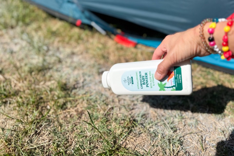 sprinkling baby powder on grass near tent