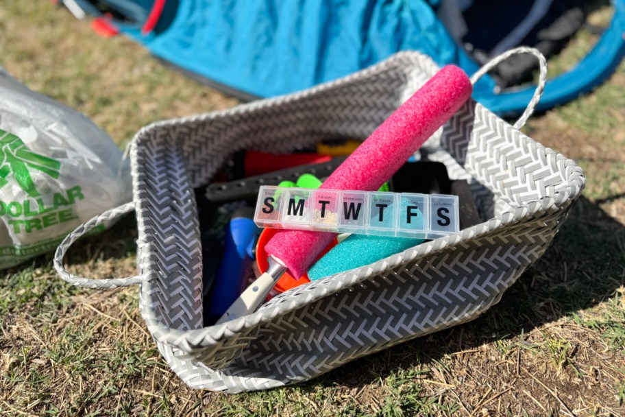 pool noodles and pill container in basket on grass
