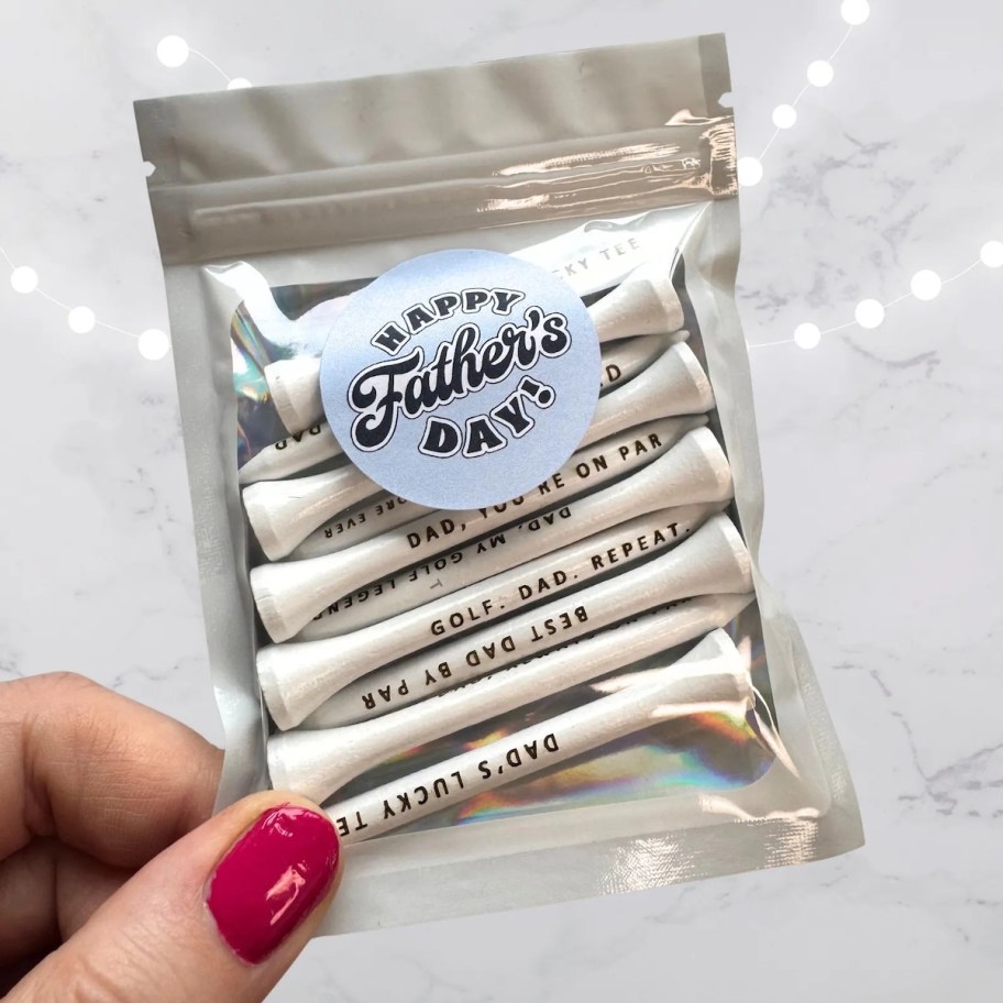 hand holding small bag of father's day golf tees