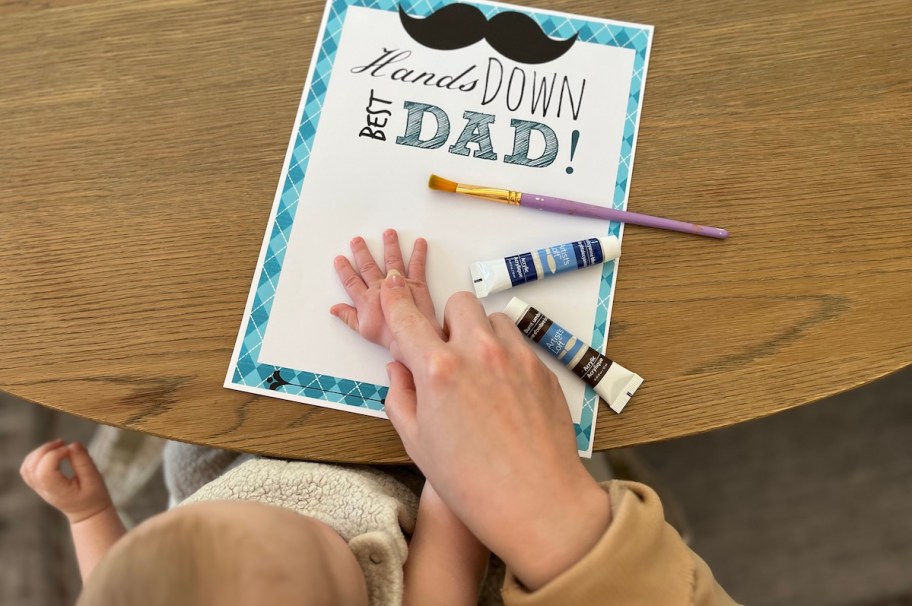 Adult pushing down babies hand on Father's Day printable