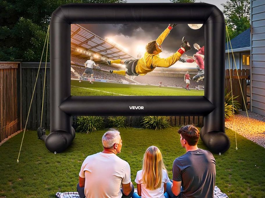 family sitting in front of an inflatable screen that is showing a soccer game