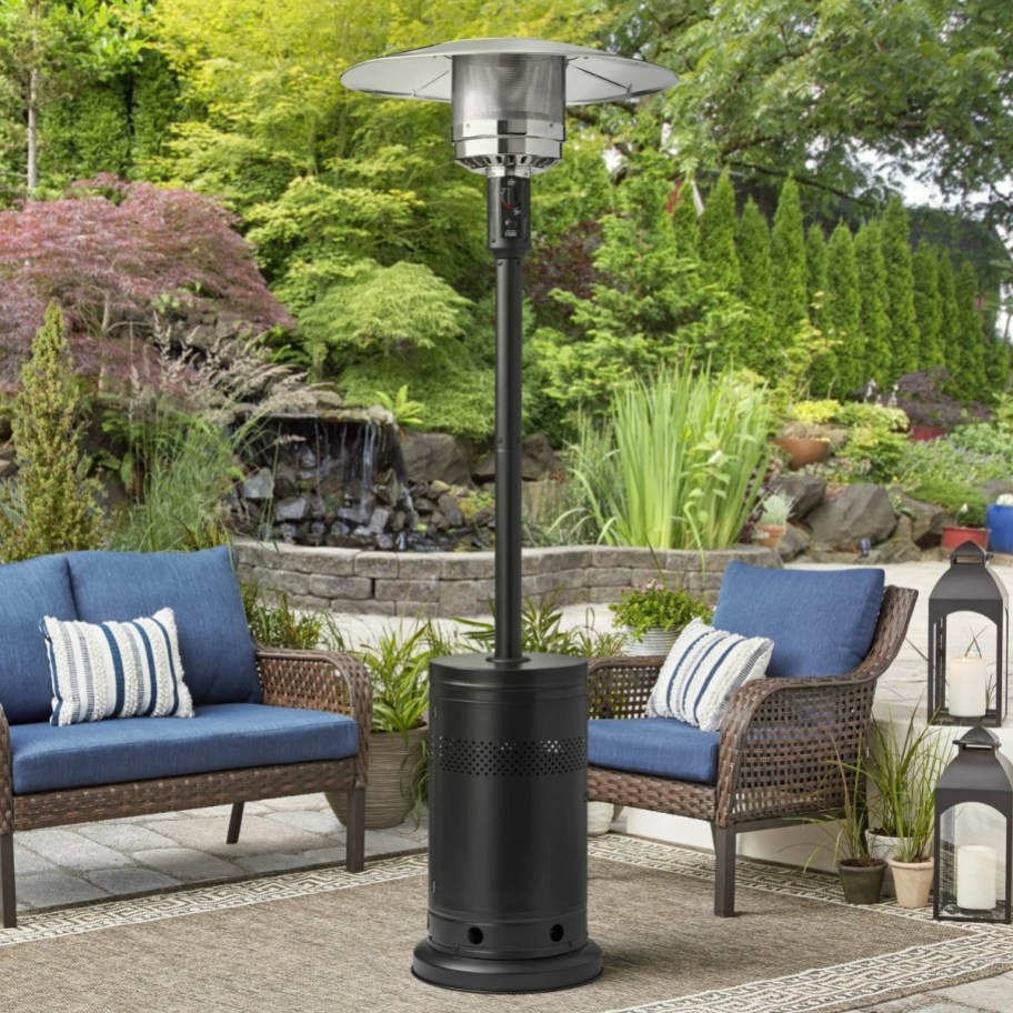 a metal freestanding patio heater on a patio shown with lounge chairs