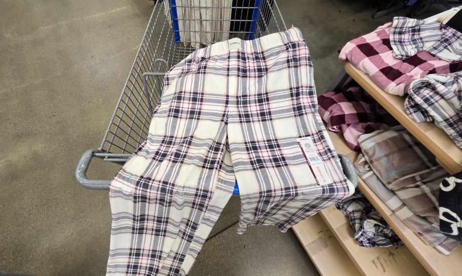 a pair of pink plaid sleep pants draped over a shopping cart