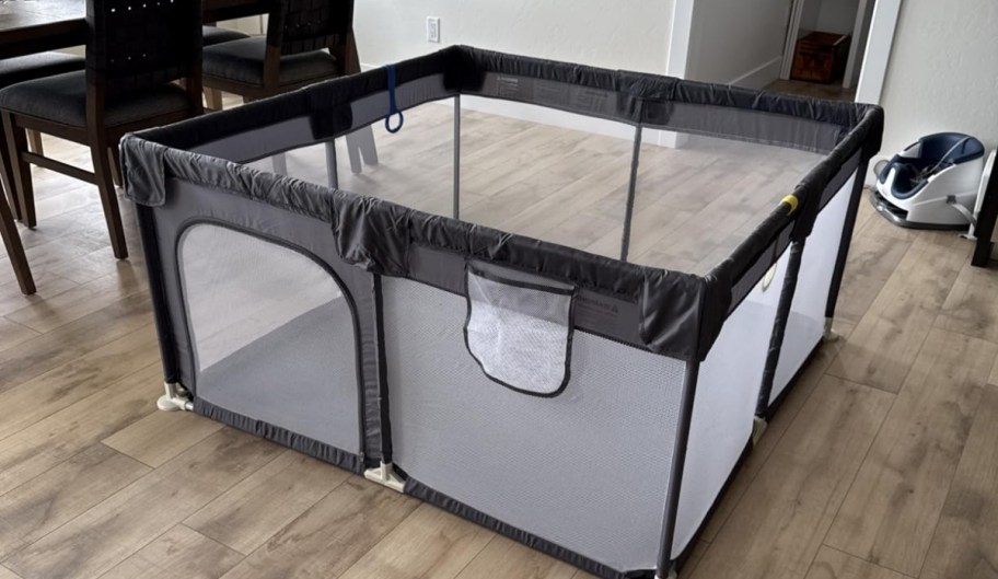 a small gray playpen assembled in a dining room