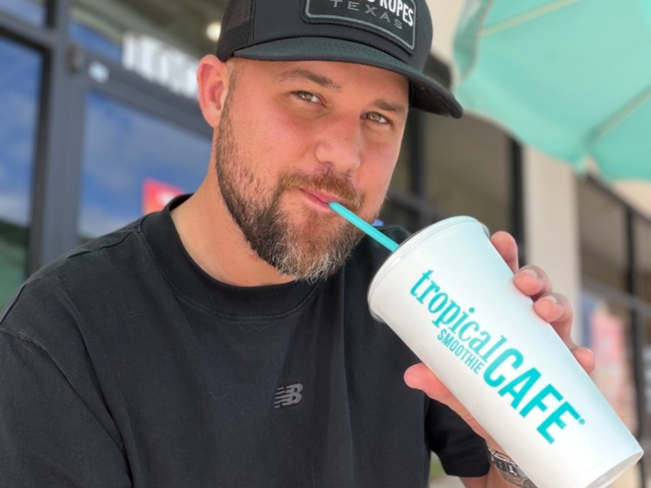 man drinking smoothie from to-go cup and straw