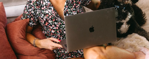 woman in pajamas on a couch with a laptop