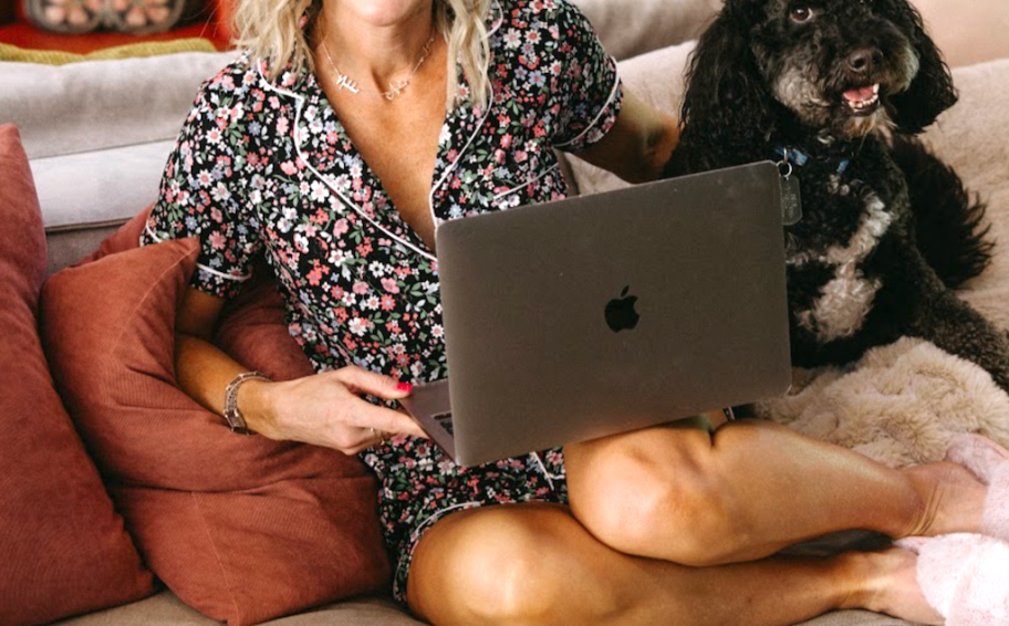 woman in pajamas on a couch with a laptop