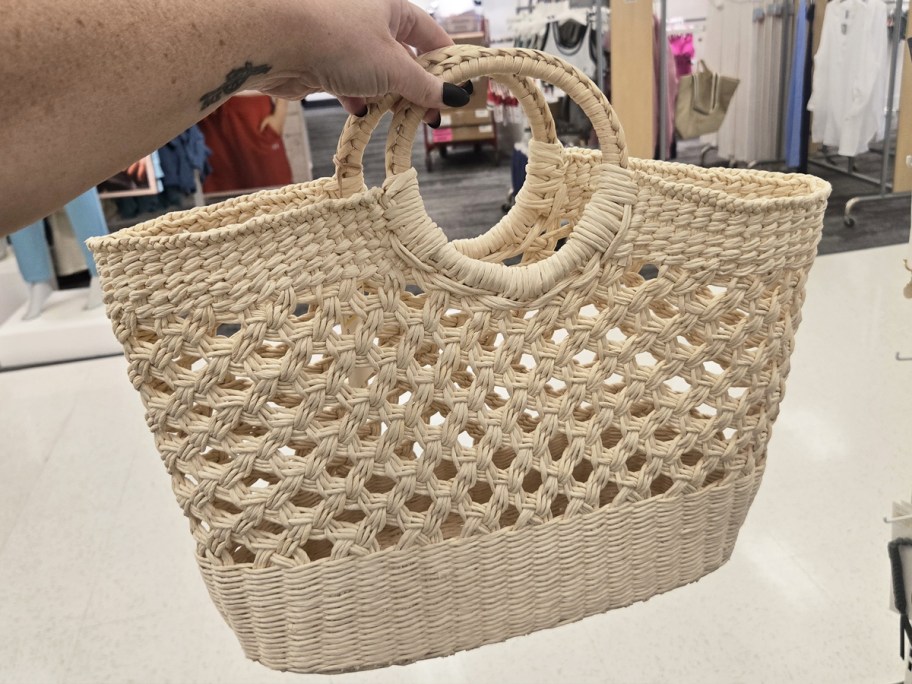 hand holding up a straw tote bag in store