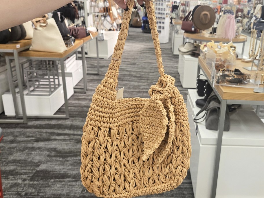 hand holding up a straw shoulder bag in store