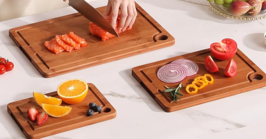 three bamboo cutting boards on counter with various fruits and vegetables on them