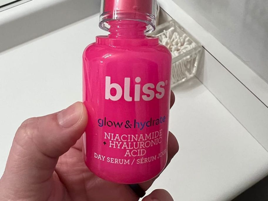 A person holding. pink bottle of Bliss