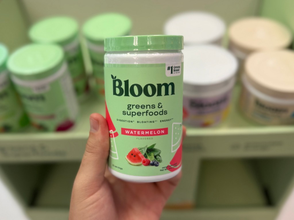 Person holding up bloom nutrition, watermelon inside GNC store