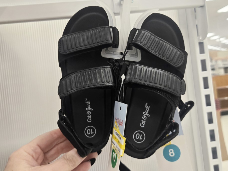 hand touching a pair of black velcro sandals