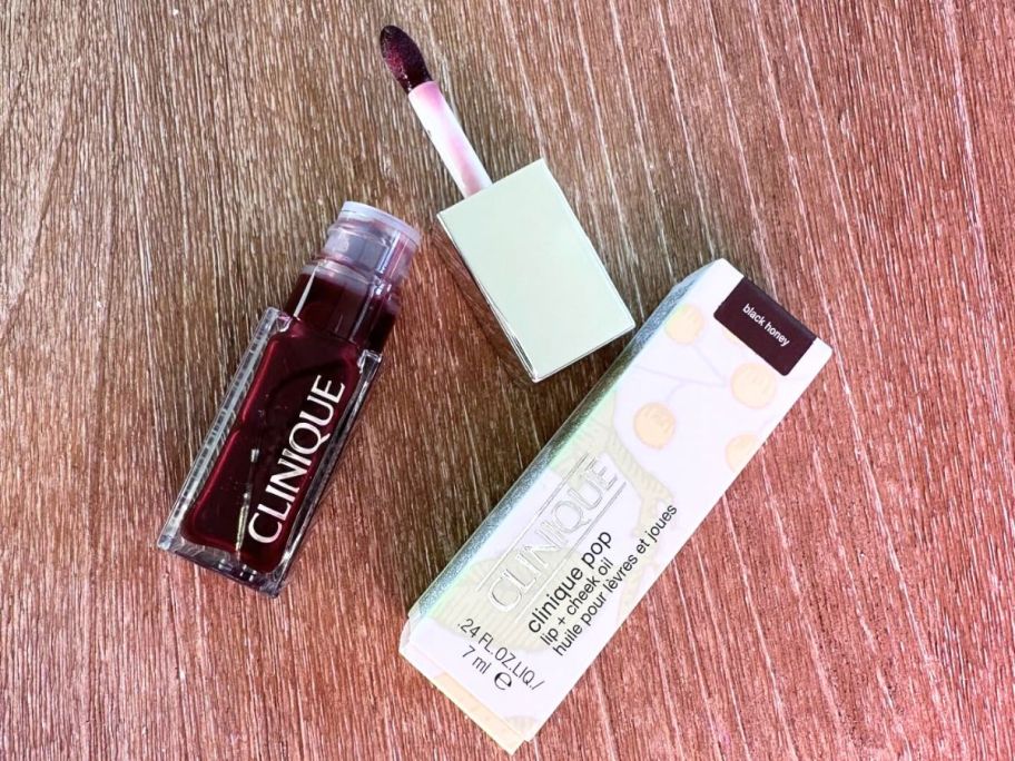 A Clinique Pop Lip + Cheek Oil in Black Honey with the wand removed from the tube and the box it comes packaged in