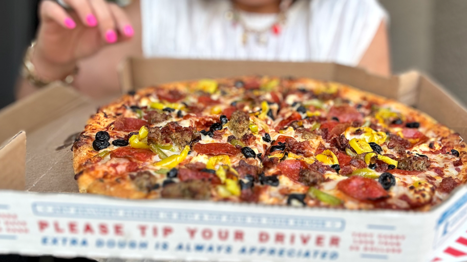 person holding a domino's pizza in box