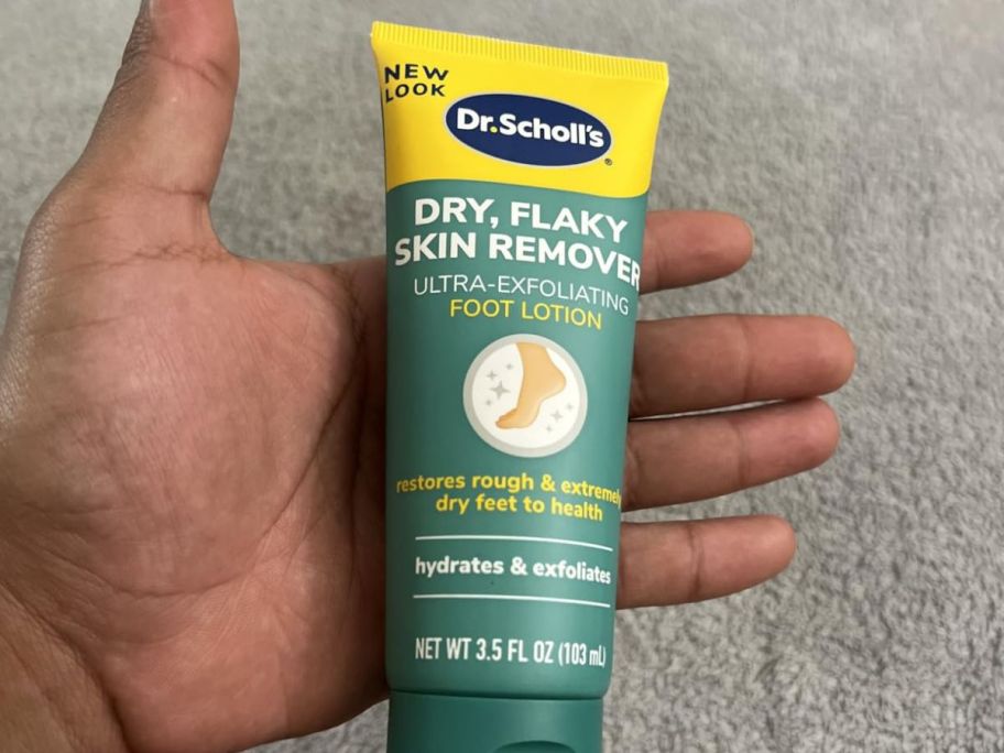 A person holding a Dr. Scholl's Dry, Flaky Skin Remover bottle
