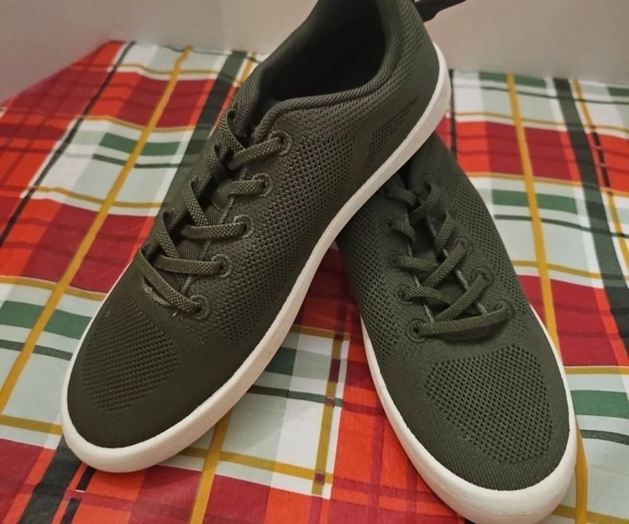 A pair of green canvas sneakers on a plaid table cloth