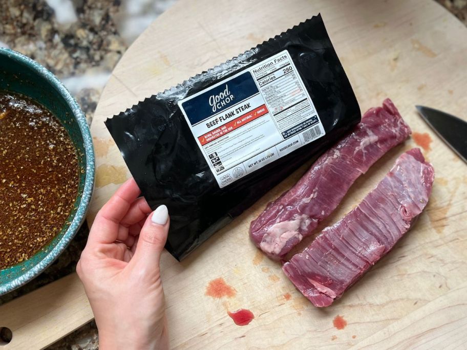 hand holding Good chop steak in its bag and on the cutting board next to its sauce