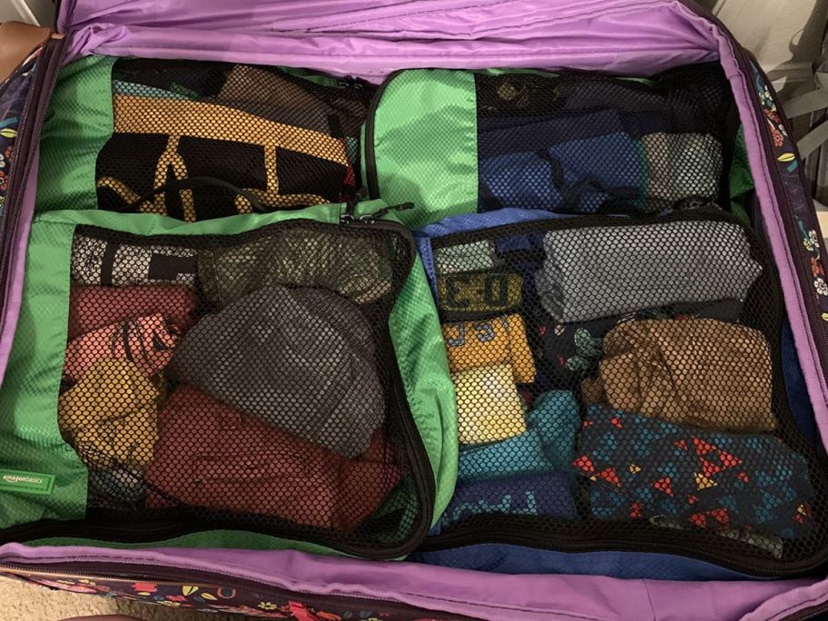 Luggage with green and black mesh packing cubes in them 