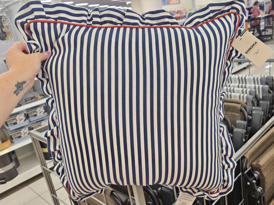 hand holding up a striped throw pillow with ruffle edges