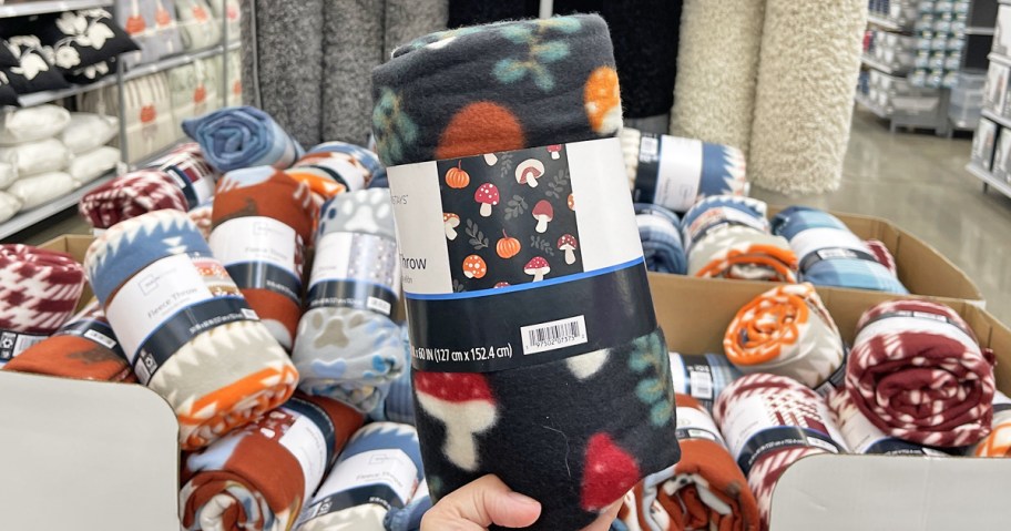 hand holding up a mushroom print throw blanket in store
