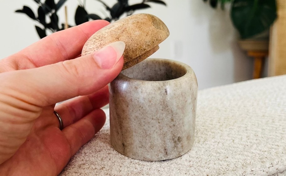 hand holding wood lid of marble canister