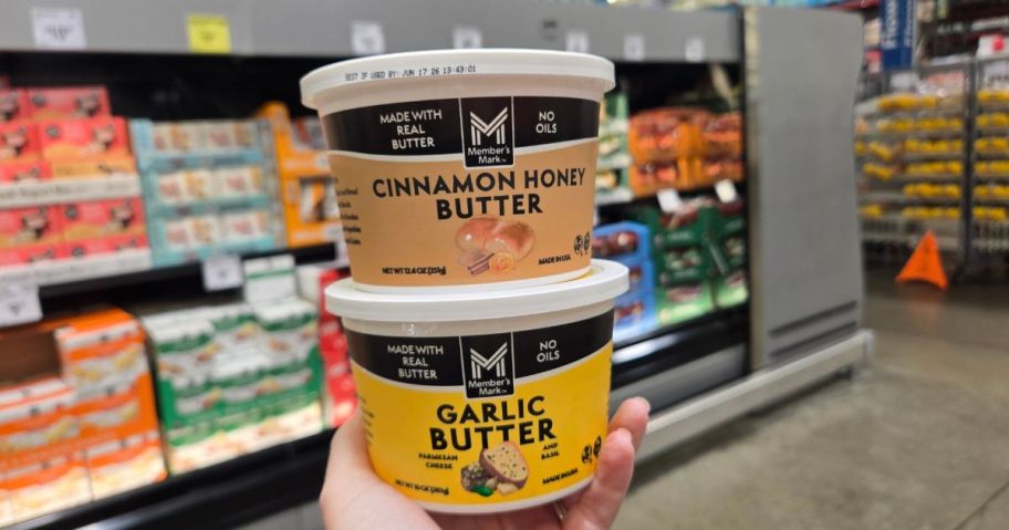 A person holding a Member's Mark Cinnamon Honey Butter and a garlic butter tub 