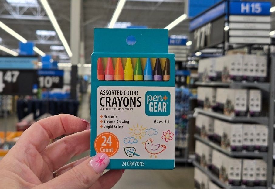 a womans hand holding a box of crayons