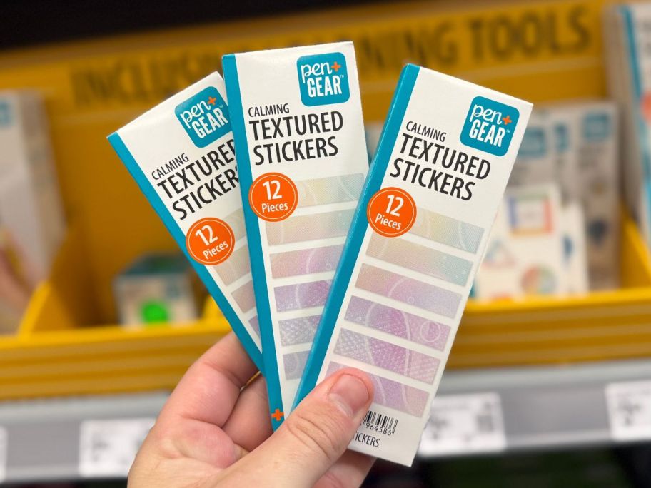 Hand holding 3 packs of Pen+Gear Sensory Textured Stickers