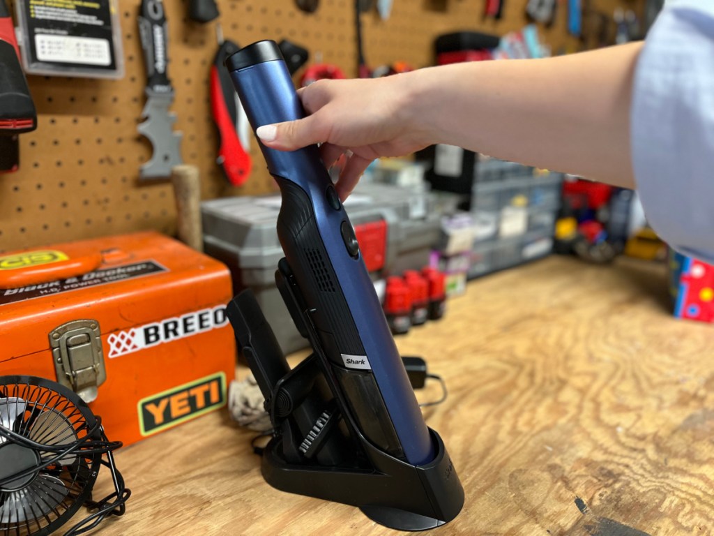 Blue shark wand vac on charger on top of wooden platform in garage