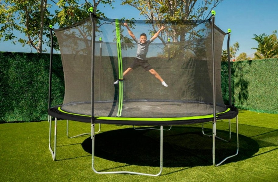 kid jumping on a large trampoline in a yard 