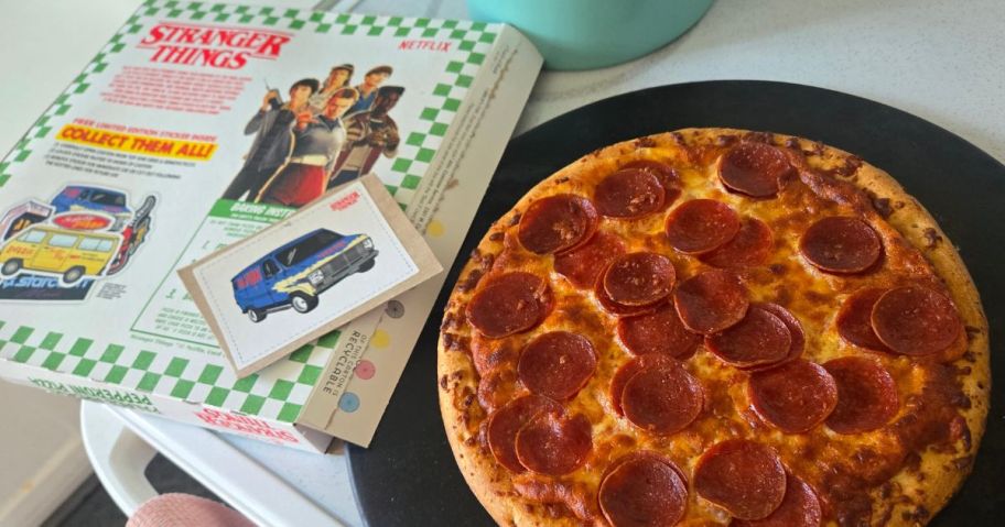 A pepperoni pizza beside a book