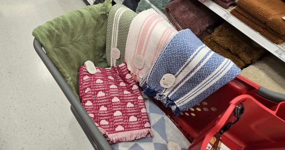 A target shopping cart with several beach towels in it and hanging on the side of it