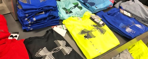 display table full of folded under armour graphic tees