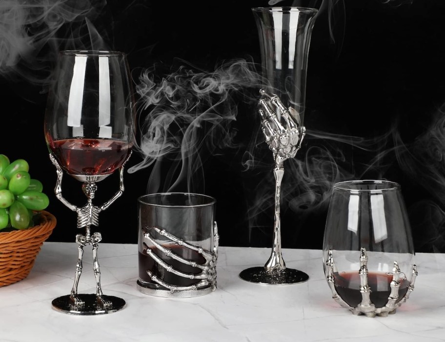 collection of silver skeleton drinkware on white table with smoke