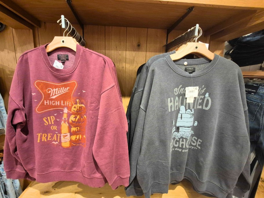 two Halloween sweatshirts hanging on a store display