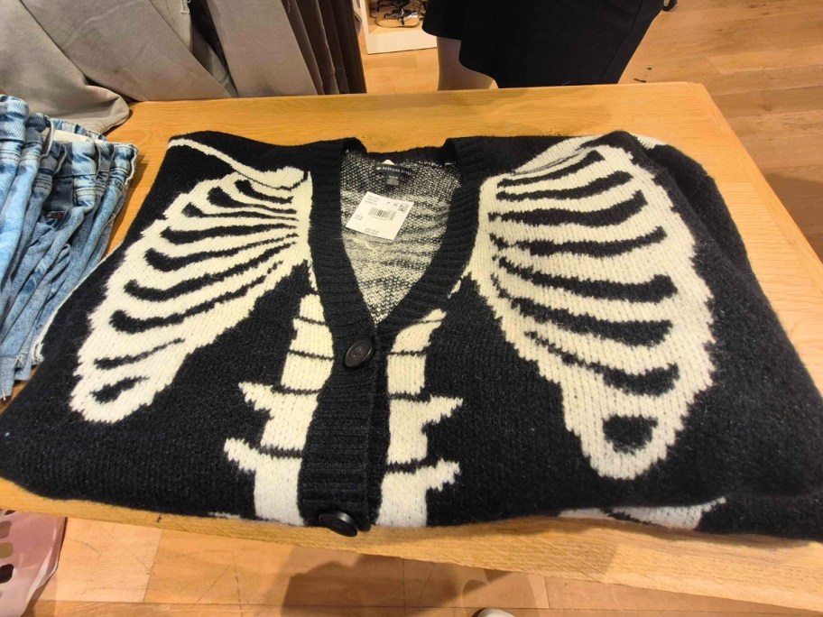 a skeleton cardigan sweater on a store display table