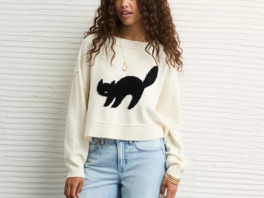 woman wearing a white sweater with a black cat on it